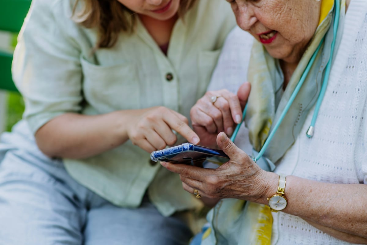 A caregiver and older adult reviewing alert notifications together on a mobile app