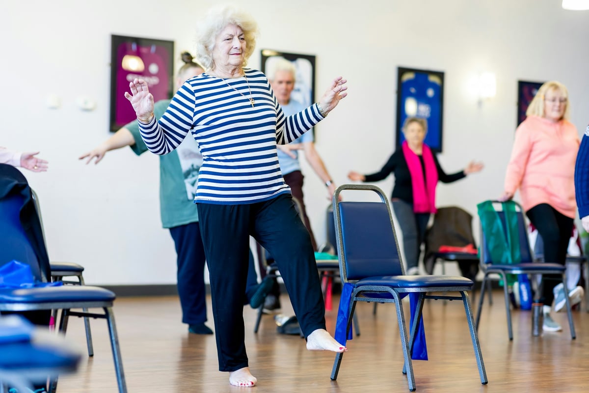 Seniors practicing balance exercises during a calm group session in a bright room
